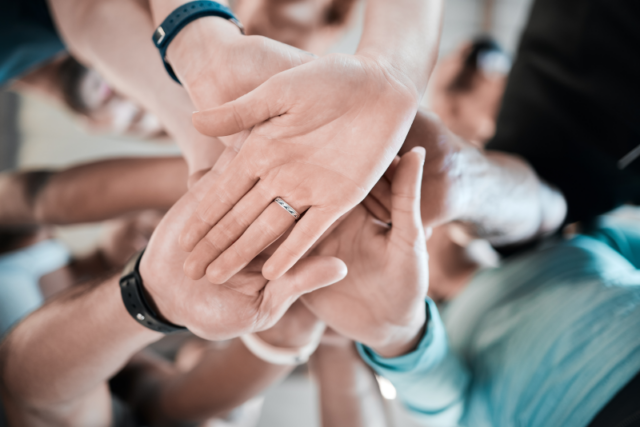 An image of teams joining hands to build workforce resilience.